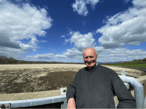 Man standing outdoors at water treatment site under blue sky.