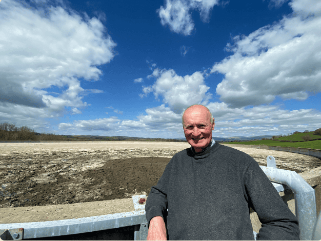 Man standing outdoors at water treatment site under blue sky.