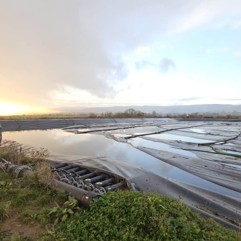 Farmer applying SlurryBugs slurry additive to reduce crust on farm lagoon.