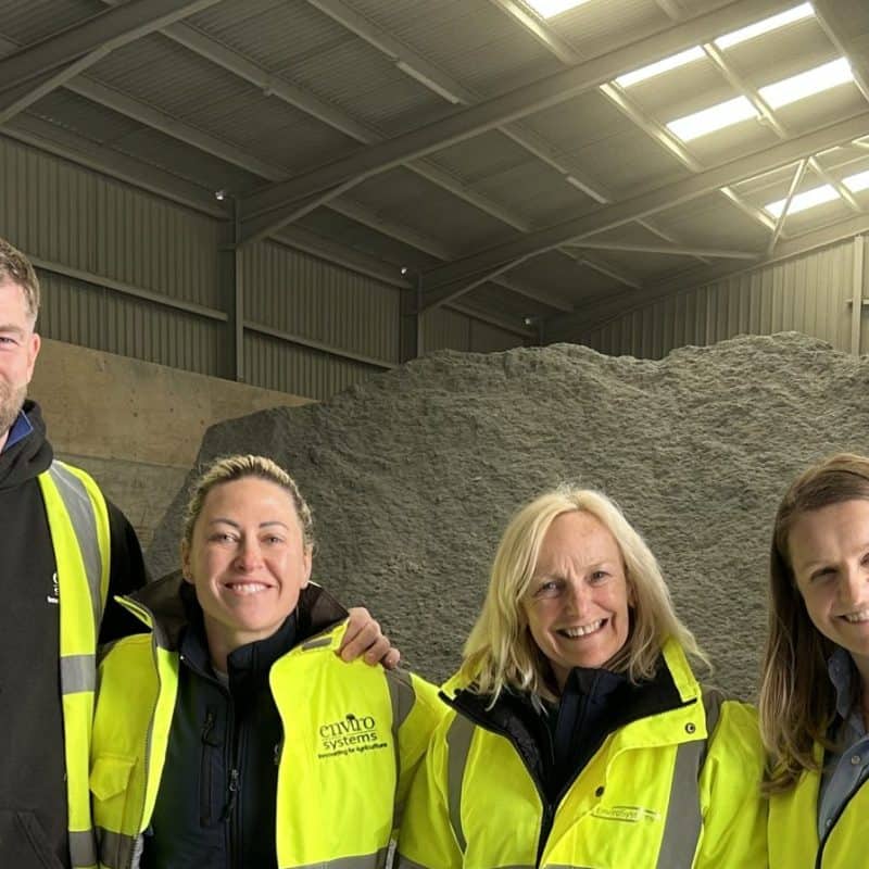 Group of four EnviroSystems employees in high-visibility jackets inside a warehouse.