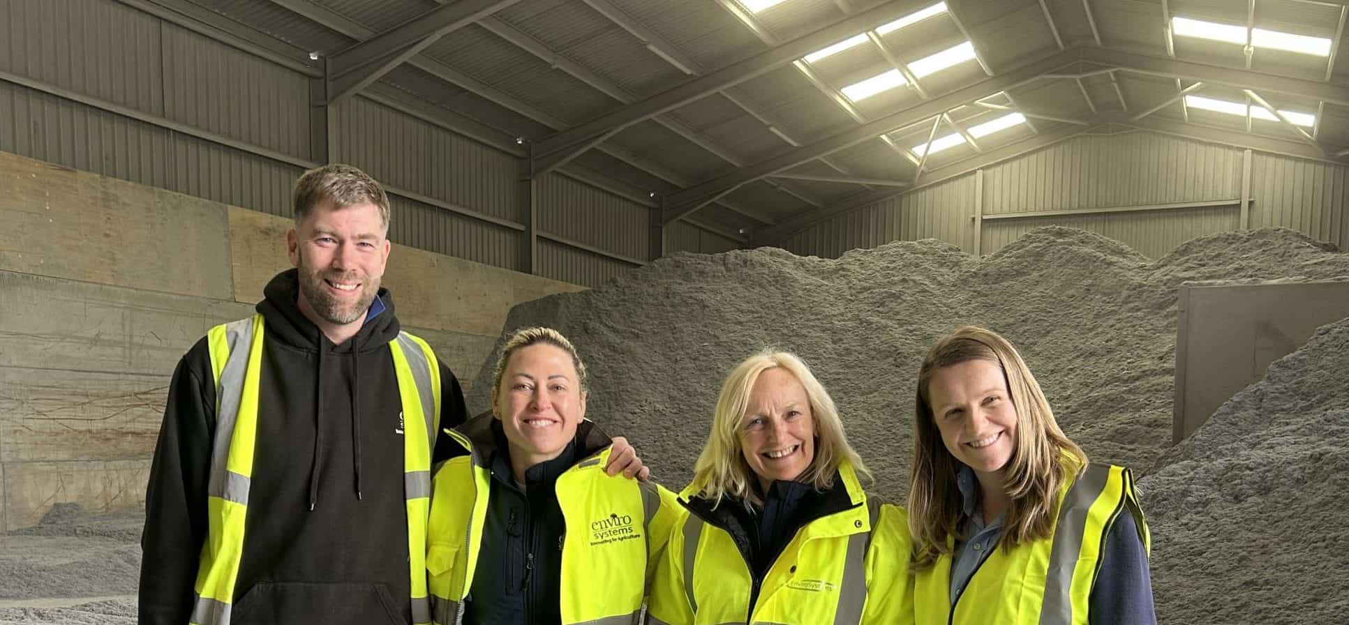 Group of four EnviroSystems employees in high-visibility jackets inside a warehouse.
